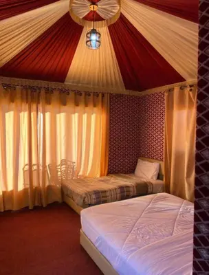 two beds in a room with a red and white tent at Welcome to Wadi Rum in Wadi Rum