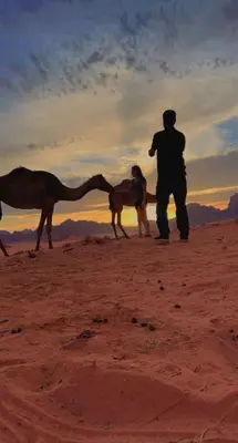 a man standing next to a camel in the desert at wadi Rum Spirit of Peace Camp in Wadi Rum