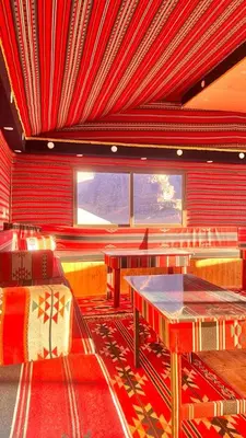 a restaurant with a table and chairs and red walls at wadi Rum Spirit of Peace Camp in Wadi Rum