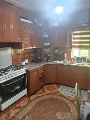 a kitchen with wooden cabinets and a stove top oven at Hello hostel in Amman
