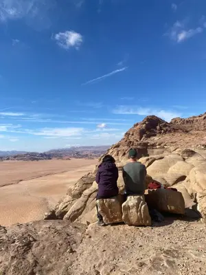 two people sitting on rocks in the desert at Wadi Rum Red Desert in Wadi Rum
