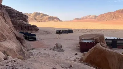 a desert with some rocks and mountains in the background at Wadi Rum Red Desert in Wadi Rum