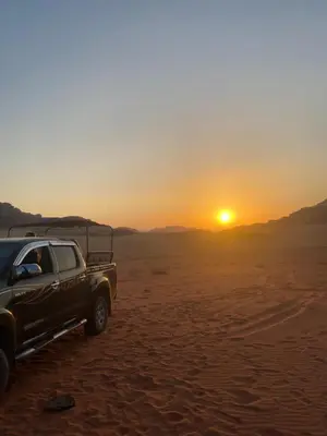 a truck parked in the desert at sunset at Wadi Rum Red Desert in Wadi Rum