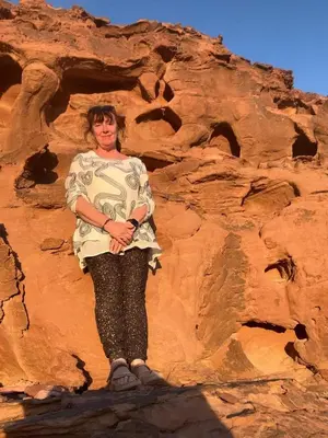 a woman standing in front of a rock formation at Wadi Rum Red Desert in Wadi Rum