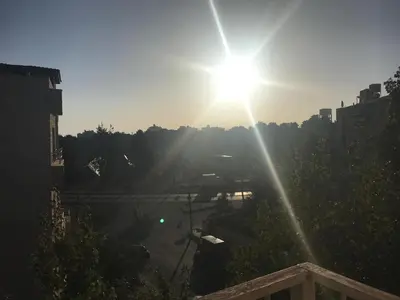 a sun is shining in the sky over a city at Amman Sweet-Home - 2 bedrooms Apartment in Amman