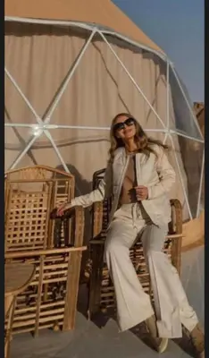 a woman sitting in a chair under an umbrella at Monica Wadi Rum in Wadi Rum