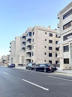 two cars parked on the side of a street next to a building at Bargos Cave in Amman