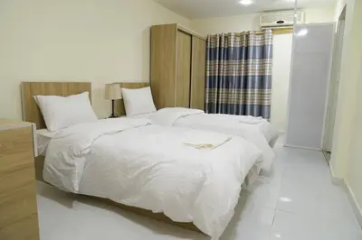 two beds in a hotel room with white sheets at Uncle Ali hotel in Wadi Musa