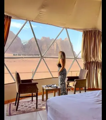 a girl standing in front of a window in a room at RUM STAR VIEW BUBBLES lUXURY CAMP in Wadi Rum
