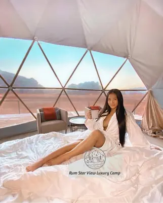 a woman sitting on a bed in a tent at RUM STAR VIEW BUBBLES lUXURY CAMP in Wadi Rum