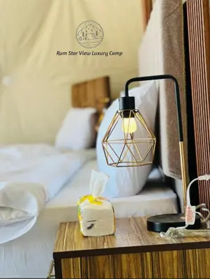 a lamp on a table next to a bed at RUM STAR VIEW BUBBLES lUXURY CAMP in Wadi Rum
