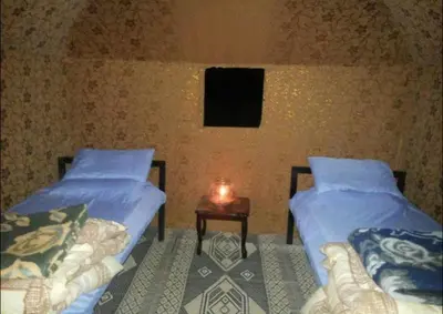 two beds in a room with a candle on a table at Wadi rum camp with tour in Wadi Rum