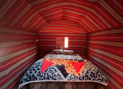 a room with a bed in a striped room at Wadi rum camp with tour in Wadi Rum