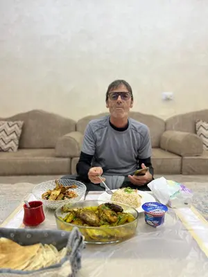 a man sitting at a table with food on it at Nora Bedouin Home in Petra