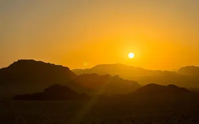 a sunset in the desert with mountains in the background at Milky Way Wadi Rum in Wadi Rum