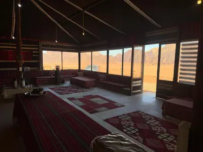 a large room with tables and rugs in a room with windows at Milky Way Wadi Rum in Wadi Rum