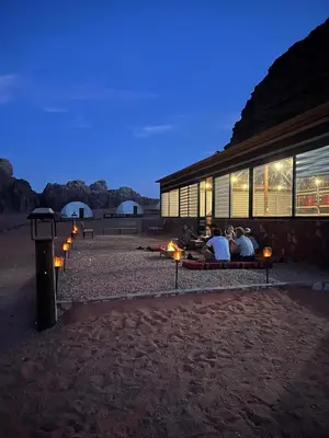 people sitting on benches outside a building at night at Milky Way Wadi Rum in Wadi Rum
