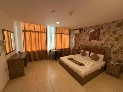 a bedroom with a bed and a table in it at El RAYYAN HOTEL SUITES in Amman