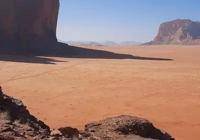 a view of the desert with a rock in the foreground at Desert Waves Camp in Wadi Rum