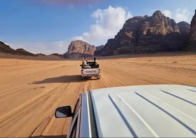 two people in the back of a truck in the desert at Desert Waves Camp in Wadi Rum