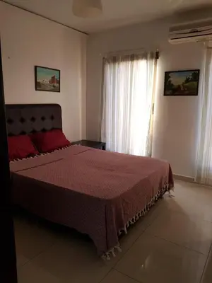 a bedroom with a bed with a red comforter and a window at Waleed's Studio in Amman
