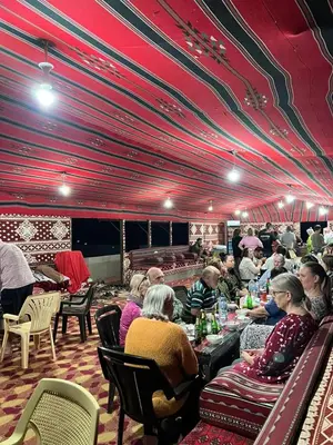 a group of people sitting at tables in a restaurant at Panorama Wadi Rum Sunset Camp in Wadi Rum