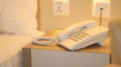 a white phone sitting on a table in a bedroom at Aysel Hotel in Aqaba