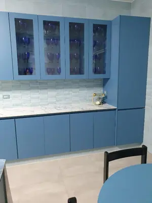 a blue kitchen with blue cabinets and a table at One-of-Kind home - city & nature in Amman