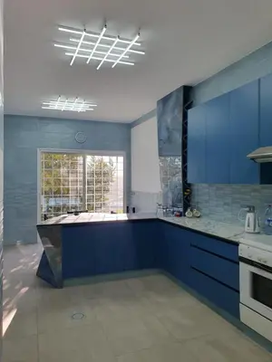 a large kitchen with blue cabinets and a window at One-of-Kind home - city & nature in Amman