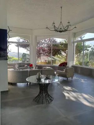 a living room with couches and a table and windows at One-of-Kind home - city & nature in Amman