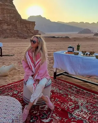 a woman sitting on a rug in the desert at Wadi Rum Jeep Tour Sleeping under the stars in Wadi Rum