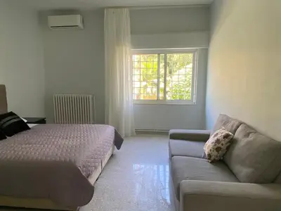 a bedroom with a bed and a couch and a window at Bright & Spacious, Upscale Amman in Amman
