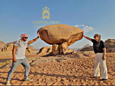 two people standing in front of a large rock at CAPITAL RUM lUXURY CAMP in Wadi Rum