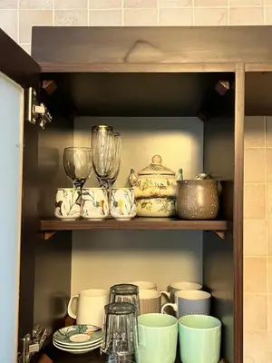 a shelf filled with dishes and cups and glasses at Modern, fully equipped apartment in Jabal Amman in Amman