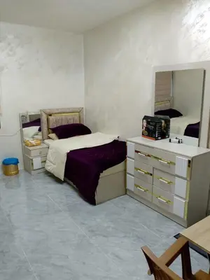 a bedroom with two beds and a dresser and a mirror at Ahmad Hostel in Kerak