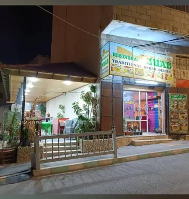 a restaurant with a sign on the side of a building at Ahmad Hostel in Kerak