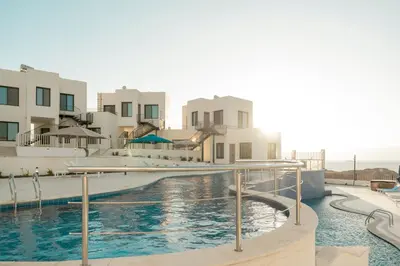 a swimming pool in front of some white buildings at Diamond Palm Hotel & Resort in Al Burj