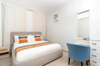 a bedroom with a bed and a blue chair at Diamond Palm Hotel & Resort in Al Burj