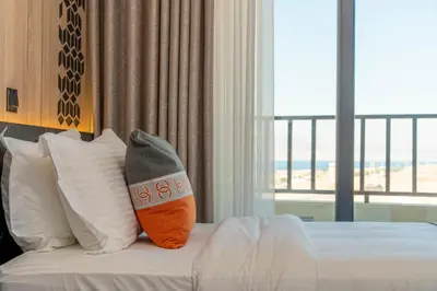 a hotel room with a bed with pillows and a window at Diamond Palm Hotel & Resort in Al Burj
