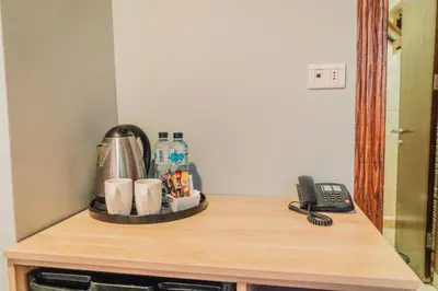 a table with a coffee maker and a phone on it at Baden Hotel Suites in Amman