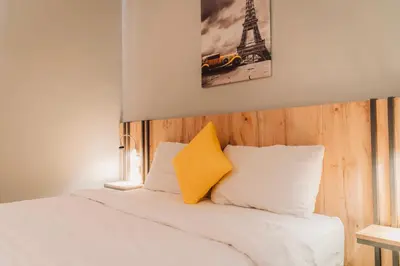 a bed with a yellow pillow and the eiffel tower at Baden Hotel Suites in Amman