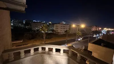 a balcony with a view of a city at night at One bedroom near University of Jordan in Amman