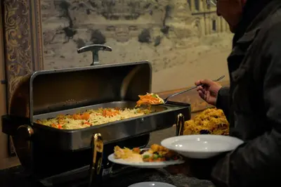 a person eating food in a pan with a plate of food at 7Wonders by TREND in Petra
