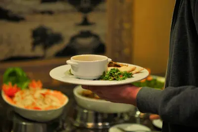 a person holding a cup of coffee and a plate of food at 7Wonders by TREND in Petra