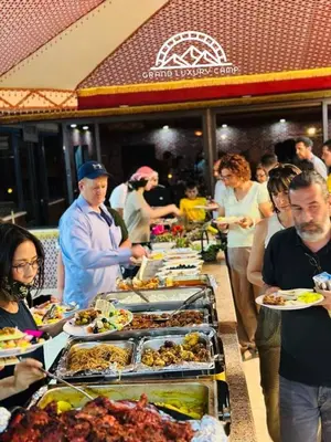 a group of people standing around a buffet of food at Grand Bubble rum luxury in Wadi Rum
