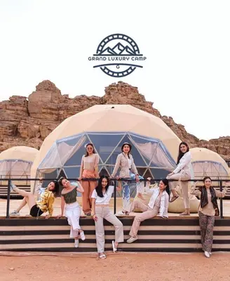 a group of people sitting on steps in front of a tent at Grand Bubble rum luxury in Wadi Rum