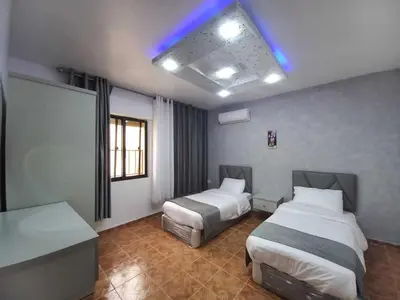a hotel room with two beds and a blue light at Al-Nujoom Hotel Suites in Amman