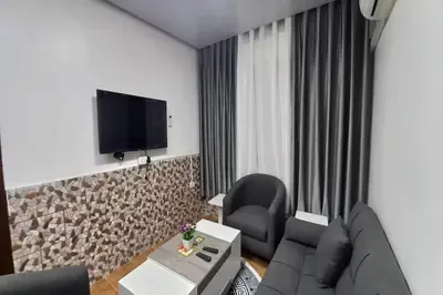 a living room with a couch and a tv on a wall at Al-Nujoom Hotel Suites in Amman