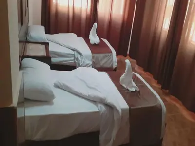 three beds in a room with white covers on them at Al-Nujoom Hotel Suites in Amman