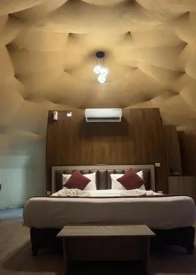a bedroom with a bed with a wooden headboard at HOlIDAY LUXURY WADI RUM in Wadi Rum
